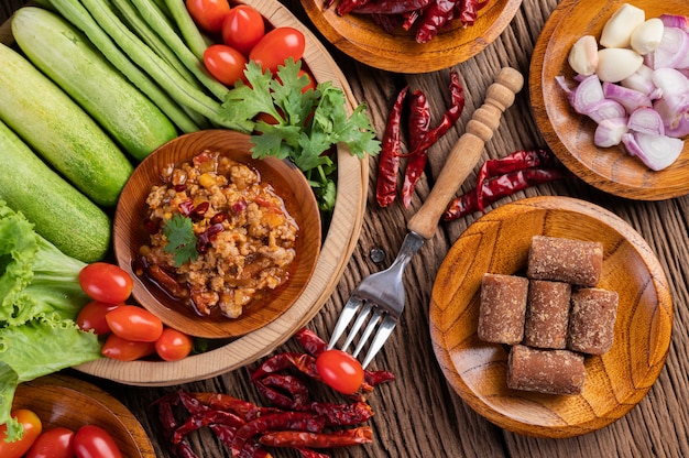 Cerdo dulce en un tazón de madera con pepino, frijoles largos, tomates y guarniciones.