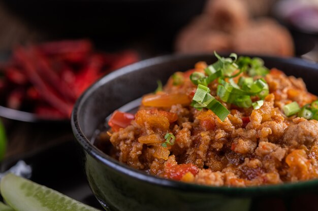 Cerdo dulce en un tazón negro, completo con pepinos, frijoles largos, tomates y guarniciones