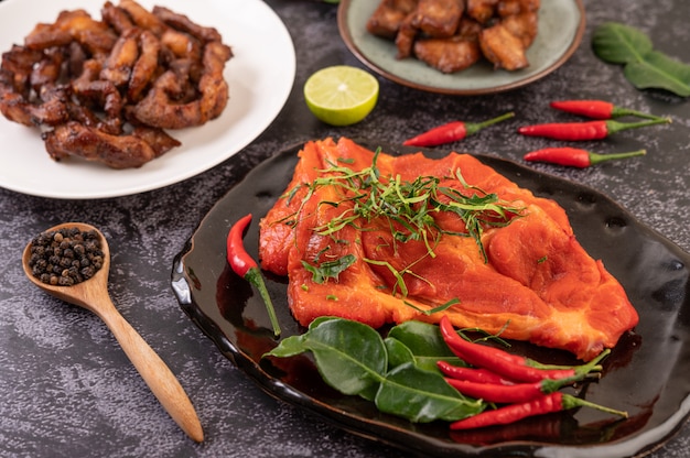 Cerdo marinado utilizado en la cocina, completo con chiles Hojas de lima kaffir en un plato negro