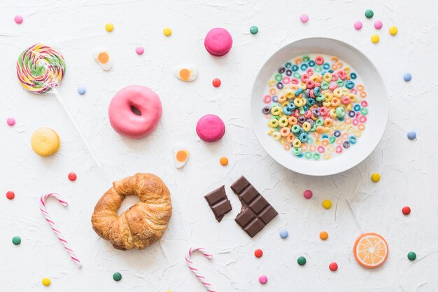 Cereal colorido en un tazón de leche sobre la comida dulce en el telón de fondo con textura