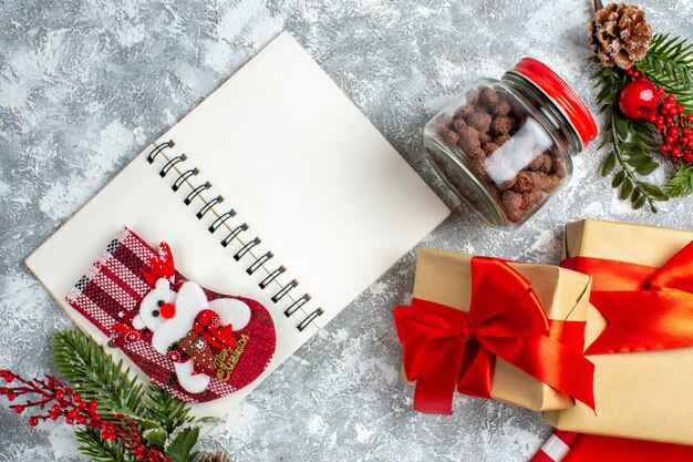 Cereal de cuaderno de calcetín de Navidad de vista superior en ramas de árbol de Navidad de tarro en mesa gris