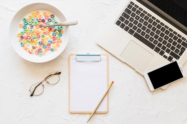 Foto gratuita cereales coloridos con lechero y portátil sobre fondo con textura