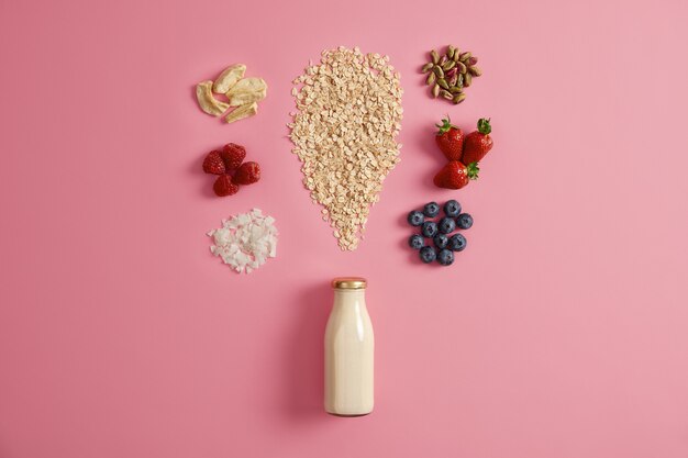 Cereales con manzanas secas, dátiles, anacardos, pistachos alrededor de botella con leche