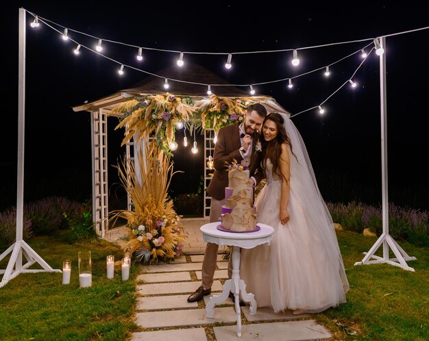 Ceremonia nocturna al aire libre de la novia con pastel de bodas tradicional