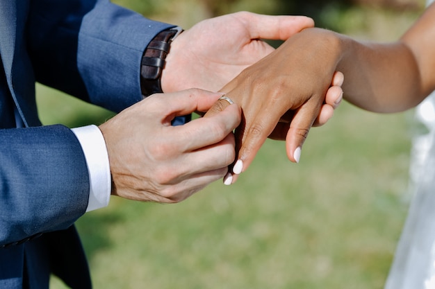 Ceremonia de poner el anillo de bodas en el dedo de la novia al aire libre