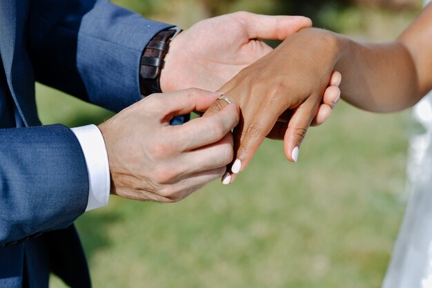 Ceremonia de poner el anillo de bodas en el dedo de la novia al aire libre