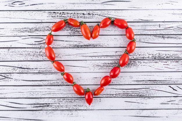 Cereza roja fresca como forma de corazón en la superficie de madera blanca