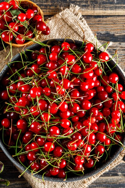 Cereza en sartén y cesta en madera y saco.