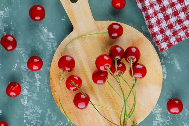 Cereza con toalla de cocina plana sobre yeso y tabla de cortar