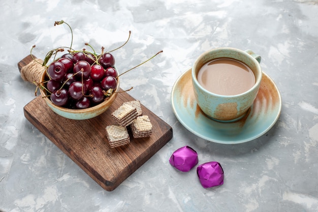 Cerezas ácidas frescas con café con leche en el escritorio gris, foto de gofres de frutas dulces