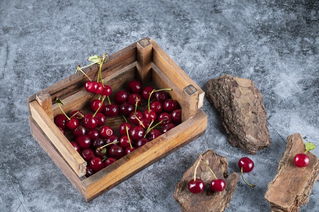 Cerezas en una canasta de madera sobre el mármol