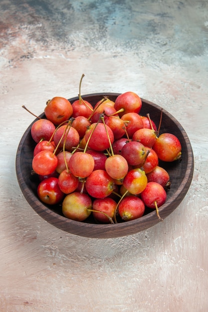 Cerezas cerezas rojo-amarillo en el cuenco de madera sobre la mesa