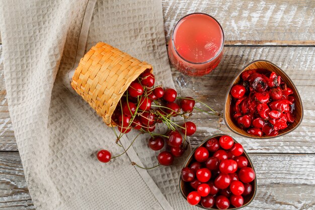 Cerezas con cóctel, mermelada en un tazón y cesta en madera y papel de cocina