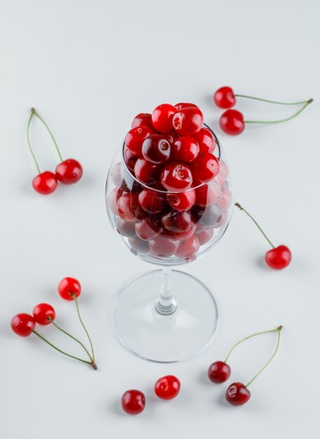 Cerezas en una copa de vino vista de ángulo alto sobre un blanco