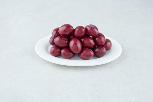 Cerezas de cornel en escabeche en un plato blanco.