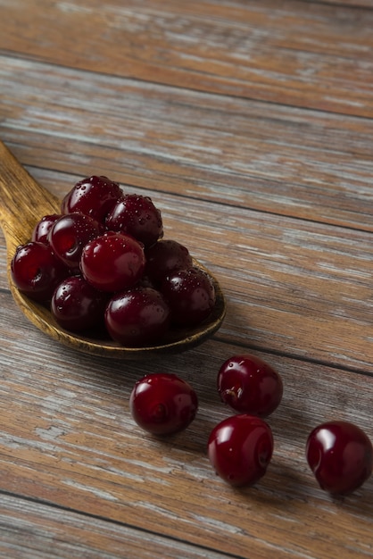 Cerezas en una cuchara sobre una mesa de madera rústica