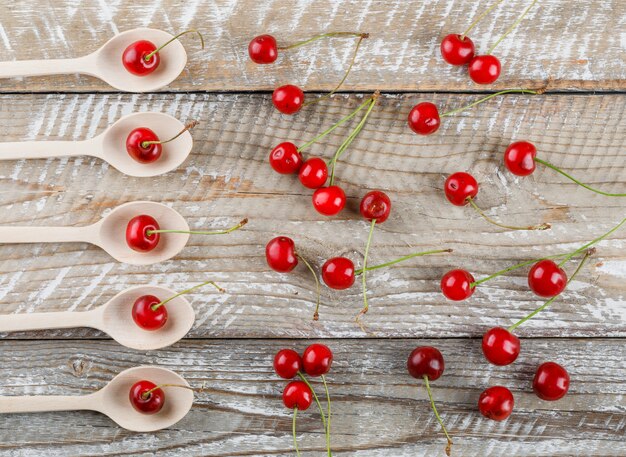 Cerezas en cucharas de madera sobre madera