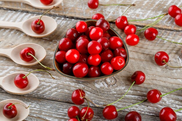 Cerezas en cucharas de madera y tazón de madera