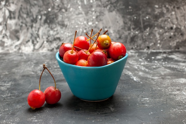 Foto gratuita cerezas frescas dentro y fuera de una canasta azul