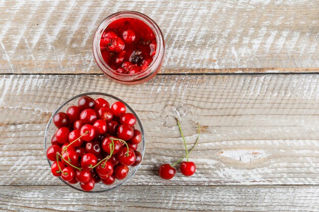 Cerezas frescas en un jarrón con mermelada de cerezas en madera