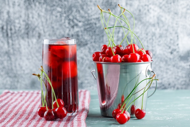 Cerezas con jugo, toalla de cocina en un cubo de yeso y espacio sucio, vista lateral.