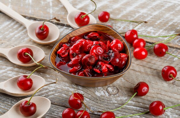 Cerezas con mermelada en cucharas de madera sobre madera