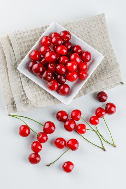 Cerezas en un plato en blanco y papel de cocina