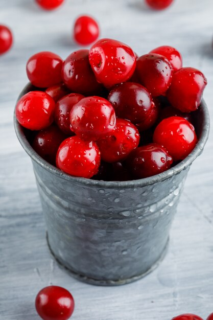 Cerezas en un primer cubo mini en un grunge gris