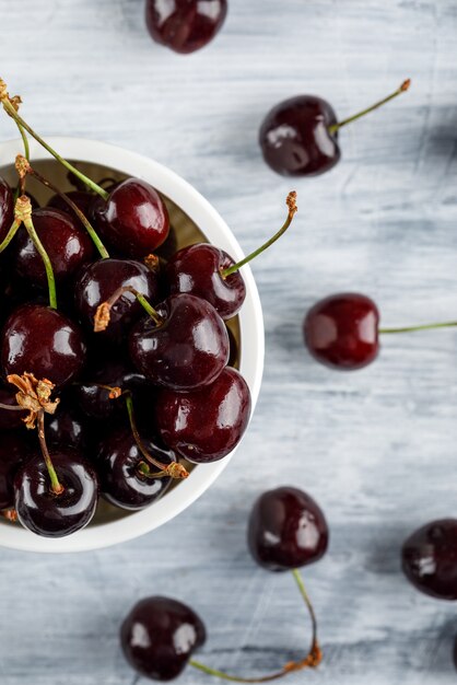 Cerezas en un recipiente en la superficie del grunge, primer plano.