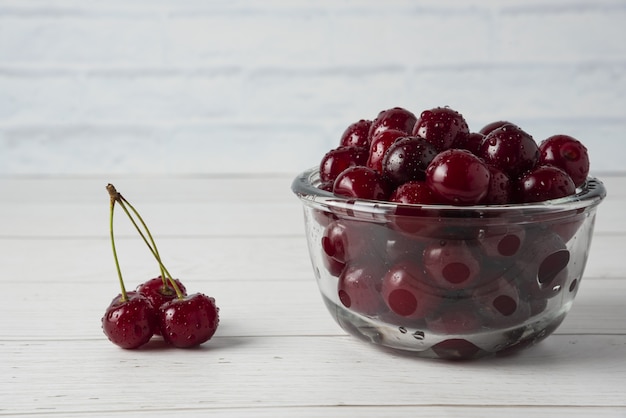 Cerezas en un recipiente de vidrio aislado sobre fondo blanco.