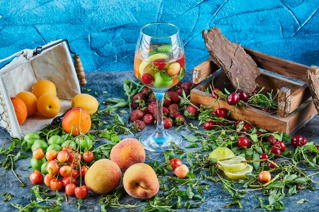 Cerezas rojas frescas en caja de madera con un vaso de jugo de frutas y frutas frescas