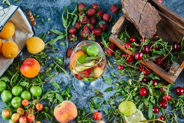 Cerezas rojas frescas en caja de madera con un vaso de jugo de frutas y frutas frescas