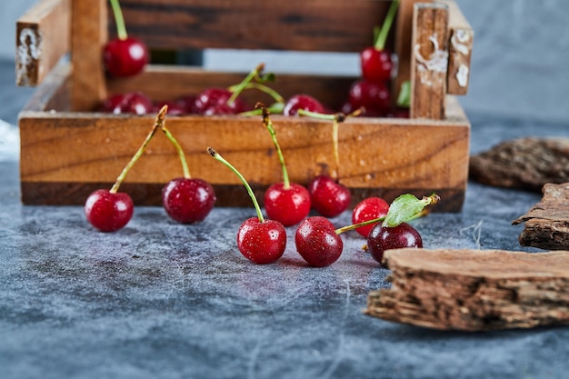 Cerezas rojas frescas jugosas en una caja de madera con hojas