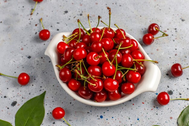 Cerezas rojas en plato tazón en mesa gris