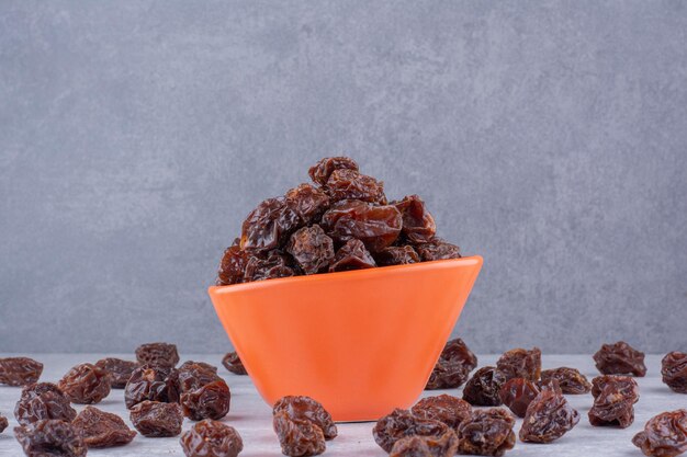 Cerezas secas marrones dentro de un plato sobre fondo de hormigón. Foto de alta calidad