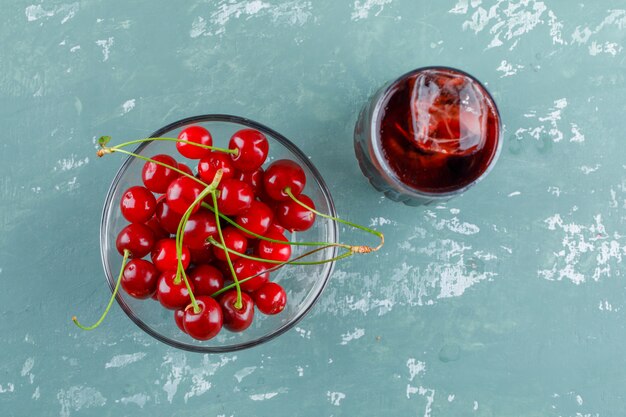 Cerezas en un tazón con jugo plano