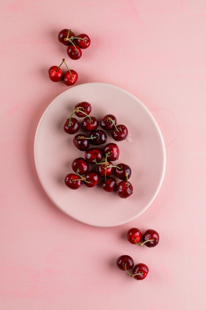 Foto gratuita cerezas en una vista superior de placa sobre una superficie rosa