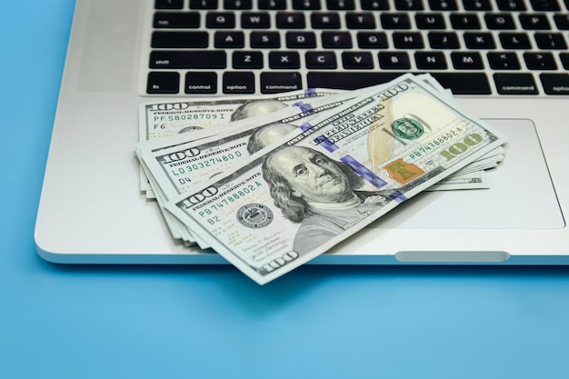 Foto gratuita cerrar billetes de dólar en el concepto de hacer dinero de la computadora portátil
