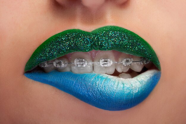 Cerrar boca labios azules y verdes con corchetes de brillo. Maquillaje de moda. Inventa la adicción. Maquillaje artístico. Disparo macro. Concepto de sensualidad y moda