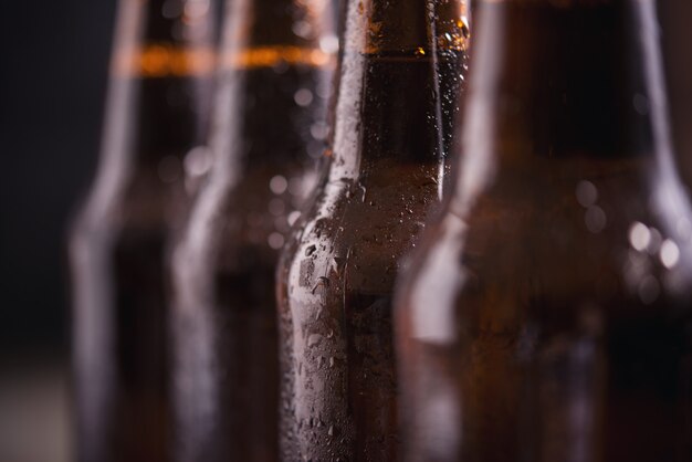 Cerrar botellas de vidrio de cerveza con hielo sobre fondo oscuro