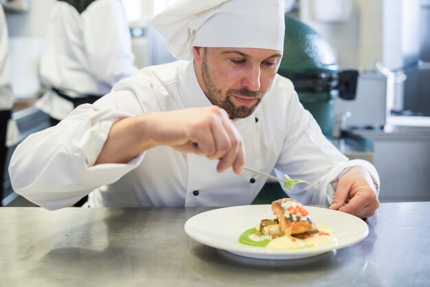 Cerrar el chef decorando el plato después de cocinar