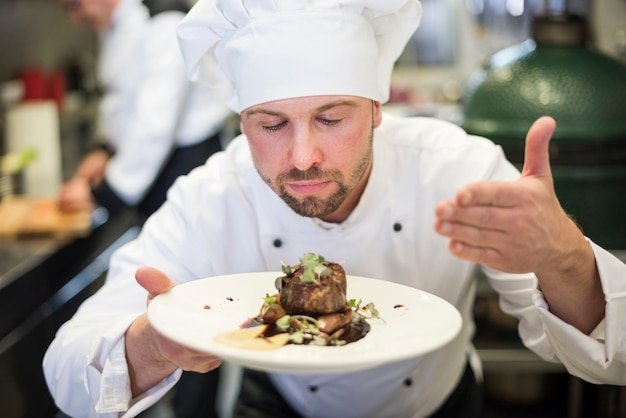 Foto gratuita cerrar el chef oliendo el plato después de cocinar