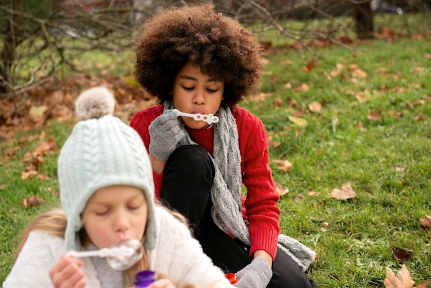 Cerrar chicas haciendo pompas de jabón al aire libre