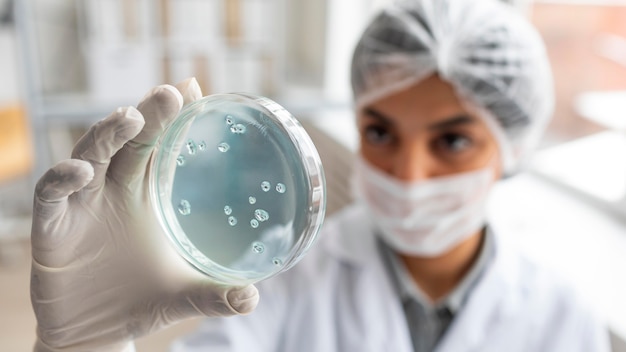 Cerrar científico borroso sosteniendo placa de Petri