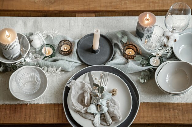 Cerrar detalle de una mesa festiva con un juego de cubiertos, un plato y velas en candelabros.