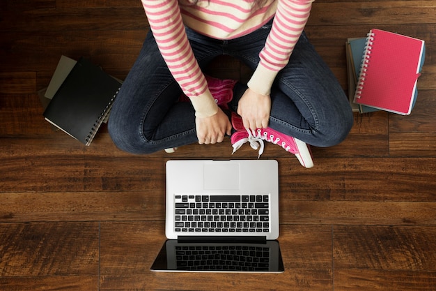 Cerrar estudiante en piso con laptop