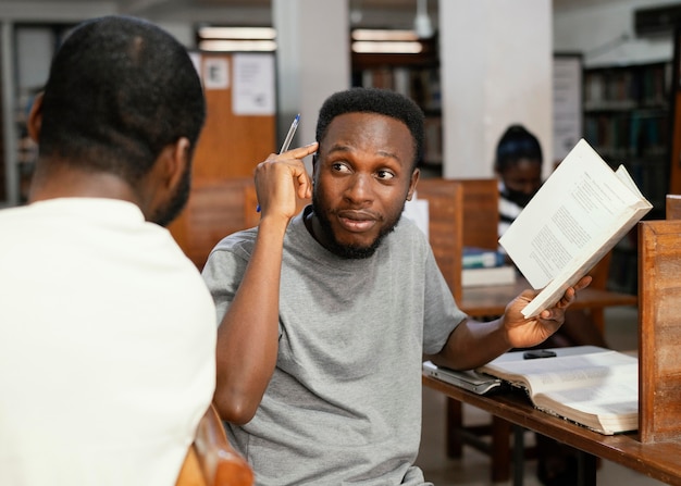 Foto gratuita cerrar a los estudiantes con el libro en la biblioteca