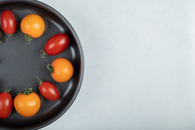 Cerrar una foto de coloridos tomates cherry en la sartén sobre fondo blanco. Foto de alta calidad