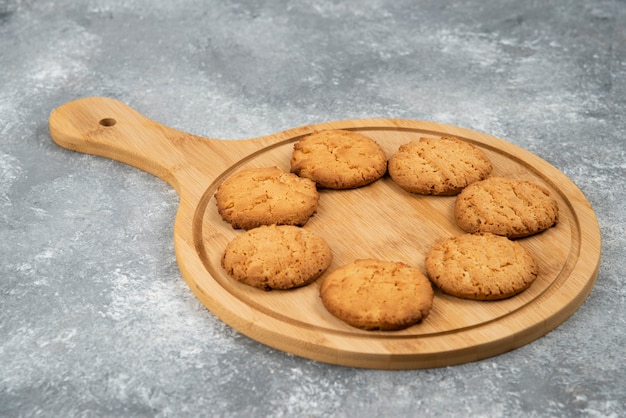 Cerrar foto de galletas caseras frescas sobre tabla de madera sobre superficie gris