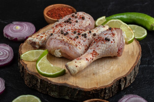 Cerrar foto de muslos de pollo marinado con verduras sobre tabla de madera.